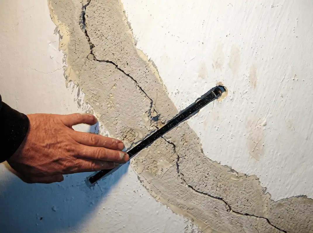 A wall with a large crack is being inspected by a professional in Chula Vista, CA